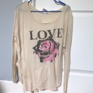 A beige long sleeve with the word love and a rose